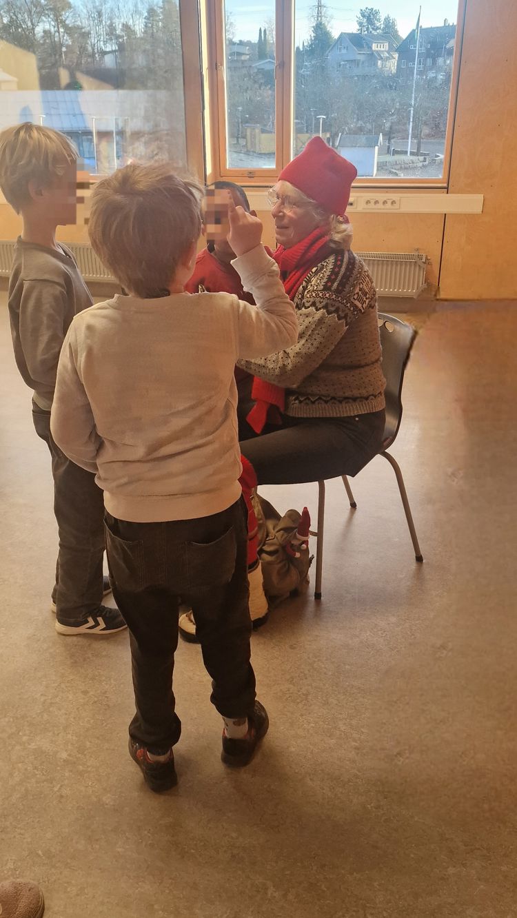 En person og et barn som ser på en person som sitter i en stol