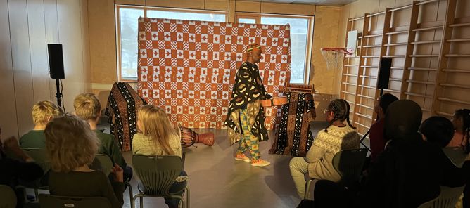 Foto: Reem Alkhatib en person i kjole som danser foran en gruppe mennesker